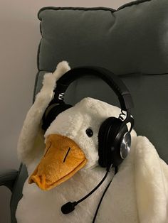 a stuffed penguin with headphones on sitting in a chair