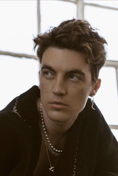 a young man with short hair and piercings on his neck wearing a black jacket