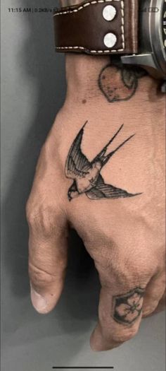 a man's hand with a bird tattoo on it