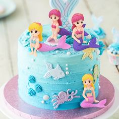 there is a blue cake with little mermaids on it