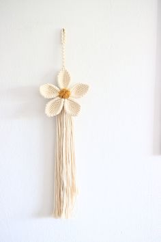 a white wall hanging with a flower on it