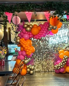 balloons and streamers decorate the entrance to a birthday party with pink, orange and gold decorations