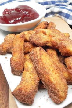 some fried food on a white plate next to a bowl of ketchup