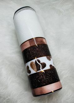 a white and brown canister sitting on top of a fur covered floor next to a candle