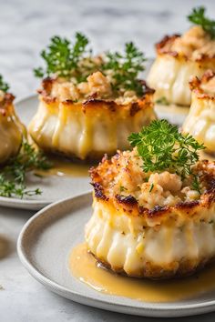 four scallops on a plate with sauce and parsley sprinkled on top