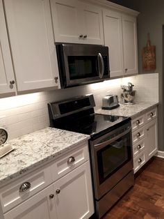 a kitchen with stainless steel appliances and white cabinets, wood floors, and hardwood flooring