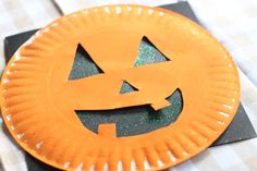 an orange paper plate with a jack - o'- lantern cut out on it