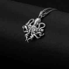 an octopus necklace is shown on a black surface