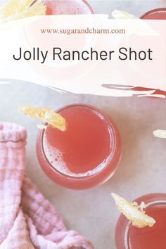 two glasses filled with red liquid sitting on top of a white counter next to a pink towel