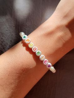 This handmade, personalized bracelet features colorful alphabet beads spelling out 'Pookie,' a playful term of endearment often used between couples. Perfect for showing your love and affection, this bracelet is crafted with care using durable elastic cord and high-quality white beads, accented by a cute heart charm. Whether you're looking for a gift for your partner or a sweet accessory to wear, this one is perfect for your "pookie" Playful Letter Beads Name Bracelet For Friendship, Alphabet Beads Bracelet, Cute Relationship, Colorful Alphabet, Relationship Bracelets, Alphabet Names, Cute Name, Sweet Accessories, Lovers Bracelet