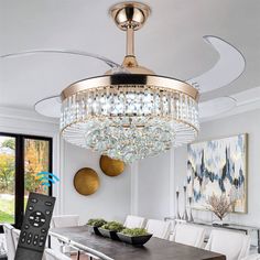 a chandelier hanging from the ceiling in a dining room with white chairs and a wooden table