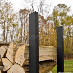 some logs are stacked next to each other in front of the trees and grass field