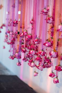 pink and orange flowers hanging from the side of a wall with sheer ribbons on it