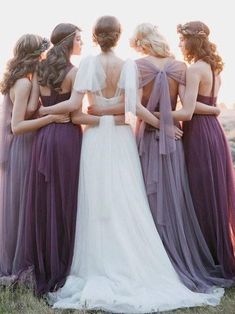 a group of women standing next to each other wearing purple gowns and veils