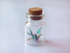 a small glass jar with a corked lid filled with leaves and a tiny cracker