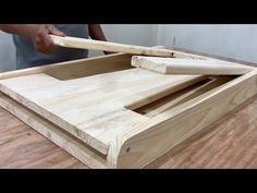 a person holding a baseball bat over a wooden box with two holes in the bottom