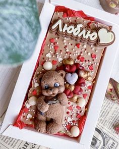 a teddy bear is in a box with hearts and nuts on it's side