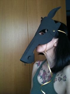 a woman wearing a horse mask in front of a wooden door with her mouth open