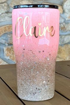 a pink and gold glitter tumbler sitting on top of a wooden table