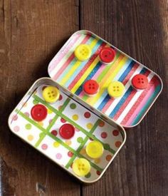 two tins filled with buttons sitting on top of a wooden table