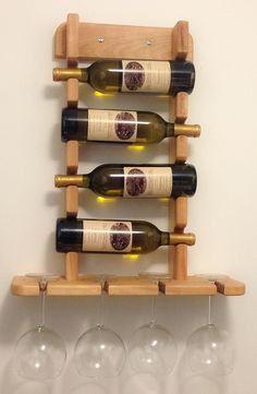 three wine glasses are sitting on a wooden rack next to four empty wine glasses in front of a white wall