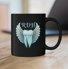 a black coffee mug with a tooth and wings on it