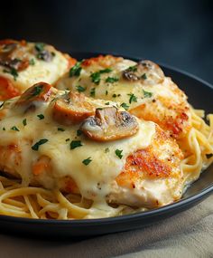 a black plate topped with chicken covered in cheese and mushrooms