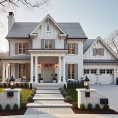 a large white house with lots of windows and columns on the front door, surrounded by greenery