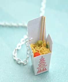 an origami box with chopsticks and noodles in it on a chain