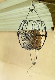 a metal bird cage hanging from the side of a building with wood balls in it