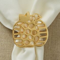 a close up of a gold brooch on a white cloth with an apple design