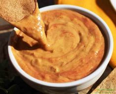 a wooden spoon is dipping some food into a white bowl with tortilla chips