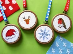 three cross stitch christmas ornaments hanging on a green surface