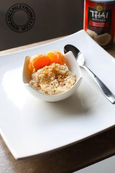 a white plate topped with oatmeal and oranges next to a can of yogurt