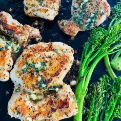 some chicken and broccoli are on a black plate next to green beans, asparagus