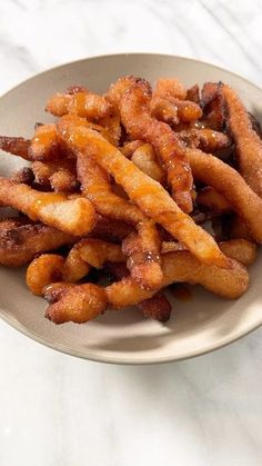 some fried food is on a plate with a silver spoon and white marble counter top