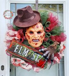 a wreath with a creepy mask on it and a sign that says elm st hanging from the front door