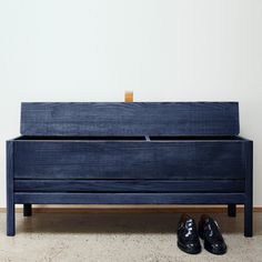 a pair of black shoes sitting on top of a blue wooden bench next to a white wall