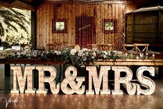 the letters mr and mrs are lit up in front of a table with flowers on it