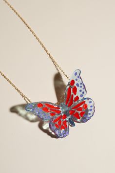 Based in: USAThis captivating piece is not just jewelry; it's a statement of individuality and elegance.Imagine a delicate butterfly, seemingly suspended in mid-flight, its wings adorned with mesmerizing red specks and intricate purple details. Each detail is meticulously crafted to capture the essence of grace and allure. This necklace is more than just an accessory; it's a reflection of your unique style and appreciation for sustainable craftsmanship. Wear it proudly to elevate any outfit, whether it's a casual ensemble or formal attire, and let it be a conversation starter wherever you go. Make a statement with this one-of-a-kind necklace! Details Made in: Broward, Florida Dimensions: 1.5" in. x 2" in. Chain length: 18" Weight: 0.1 oz. Metal: gold-plated chain Material: soy-based resin Red Butterfly Charm Necklace, Butterfly Charm Necklace For Party, Red Butterfly Necklace For Gift, Unique Multicolor Butterfly Jewelry, Whimsical Red Party Jewelry, Red Butterfly-shaped Jewelry Gift, Red Butterfly Jewelry For Gift, Handmade Unique Butterfly Shaped Necklace, Handmade Unique Butterfly Necklace