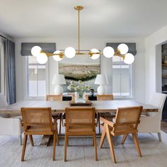 a dining room table with chairs and lights hanging from it's centerpieces