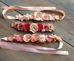 three ribbons with flowers on them sitting on top of a wooden table next to each other