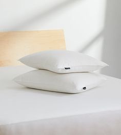 two pillows sitting on top of a white bed