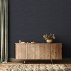 a wooden cabinet sitting on top of a hard wood floor next to a plant in a vase