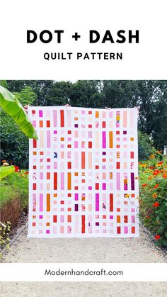 a colorful quilt hanging on the side of a garden path with text overlay that reads dot + dash quilt pattern