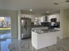 an empty kitchen with marble counter tops and stainless steel appliances in the middle of it