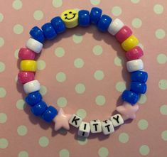 a close up of a beaded bracelet on a polka dot background with the word kitty spelled out