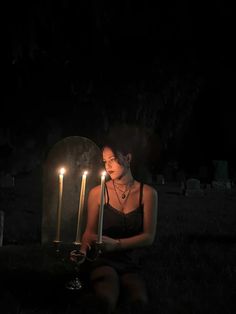 a woman sitting in the dark with three candles