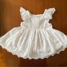 a white dress is hanging up on a wooden door with lace trimming around it