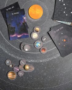 an assortment of planets and their names on a table with space themed items around them